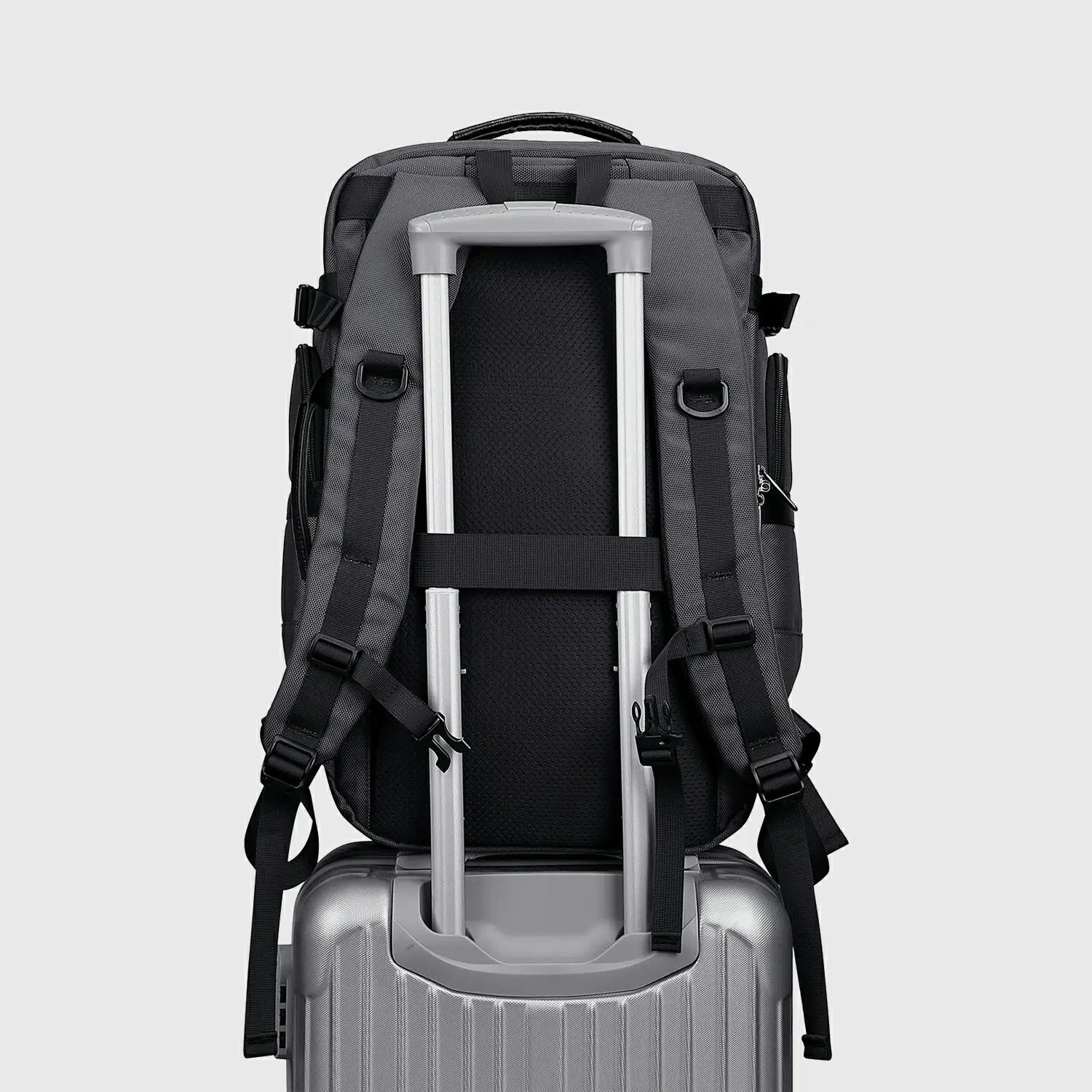 Silver grey carry on backpack attached to rolling luggage with rear suitcase strap