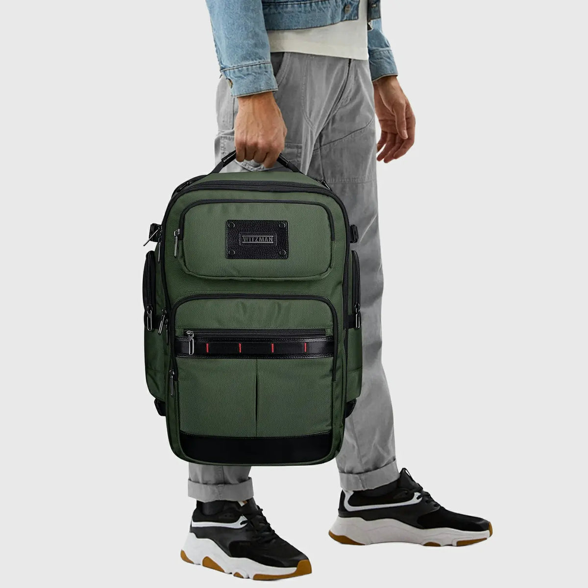 Army green travel backpack carried by the top handle for airport and business travel