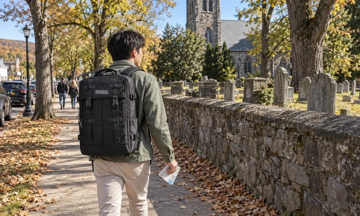 Male traveler walking beside a Sleepy Hollow cemetery wall with a black WITZMAN B716 30L backpack