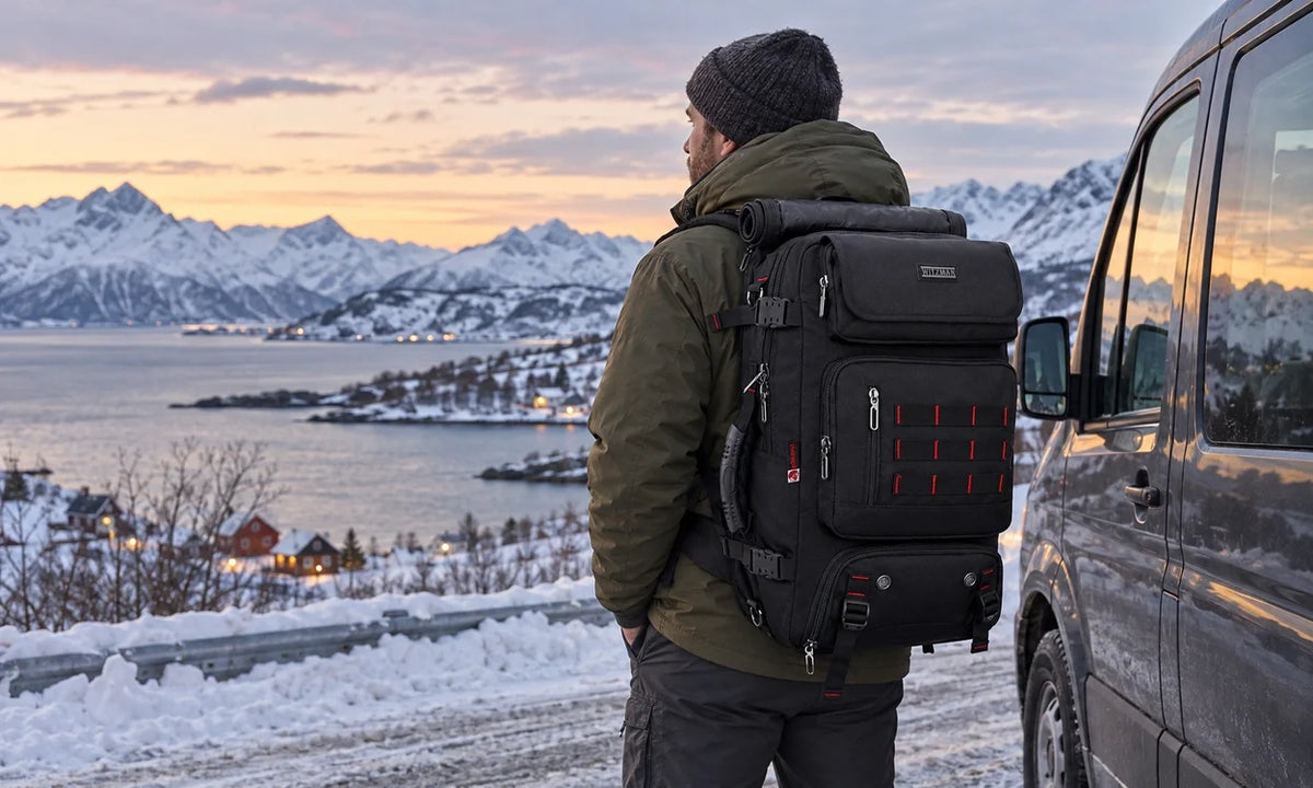 Man wearing a black WITZMAN B682 40L backpack beside a minibus on a snowy fjord road at twilight