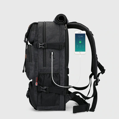 Side view of black canvas travel backpack with USB charging port and padded shoulder straps