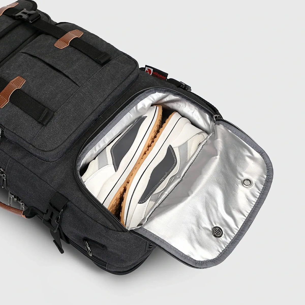 Close-up of ventilated shoe compartment inside black canvas travel backpack for men