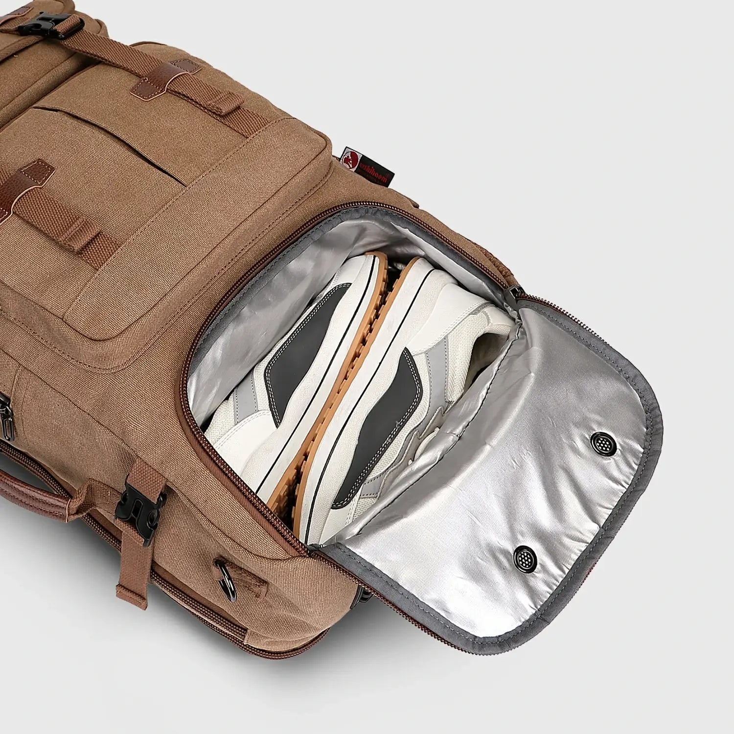Close-up of ventilated shoe compartment inside brown canvas travel backpack for men