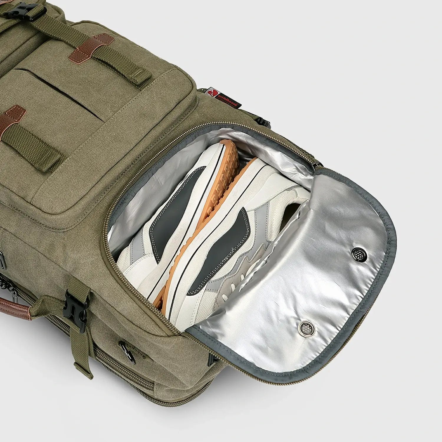 Close-up of ventilated shoe compartment inside army green canvas travel backpack for men